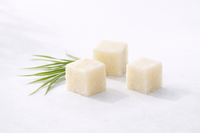 Three cubes of white soap with a green leaf on a light gray background